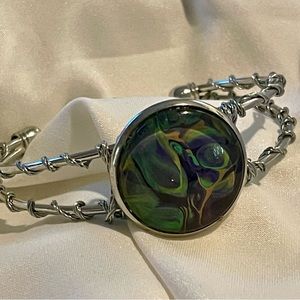 Handmade paint pouring bracelet with decorative wire wrapping.